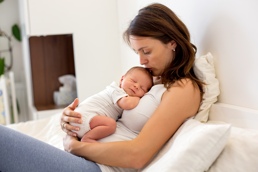 Young,Mother,Lying,In,Bed,With,Her,Newborn,Baby,Boy,